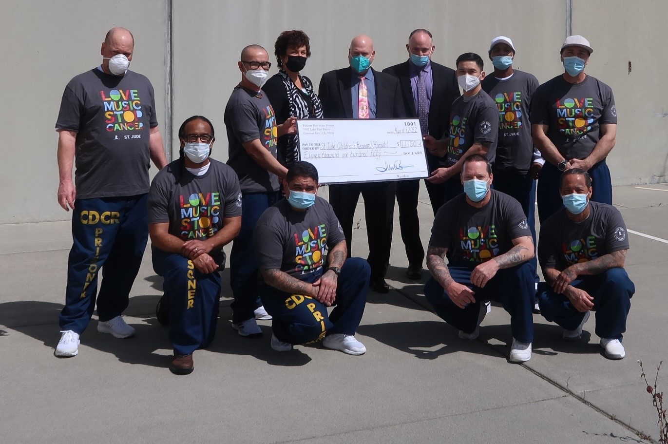 Incarcerated men and prison employees hold up an oversized check for St. Jude Children's Research Hospital
