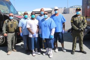 Incarcerated men and two correctional officers at a prison.