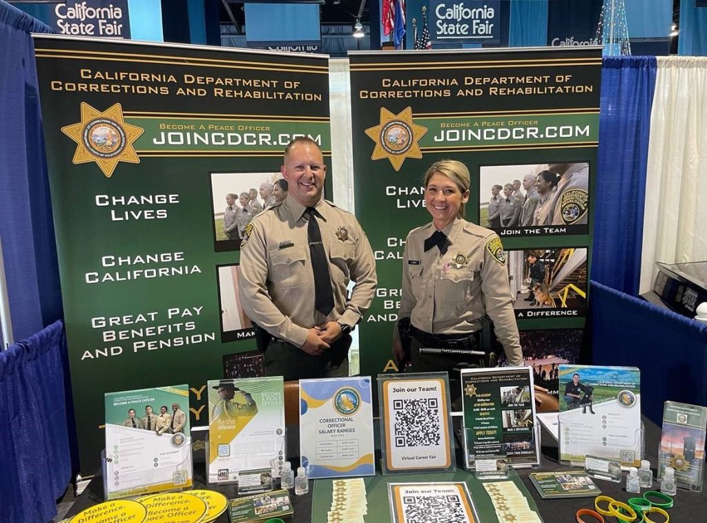 Two Mule Creek prison correctional officer recruiters in a booth.