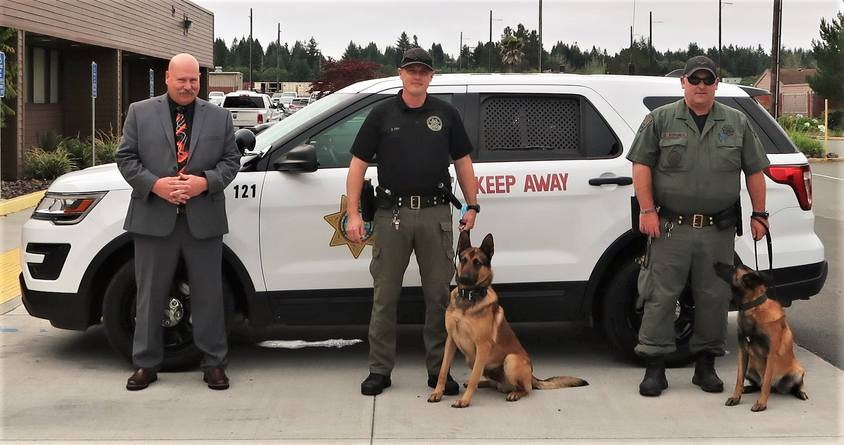 Two Pelican Bay prison K-9 officers with dogs and prison warden.
