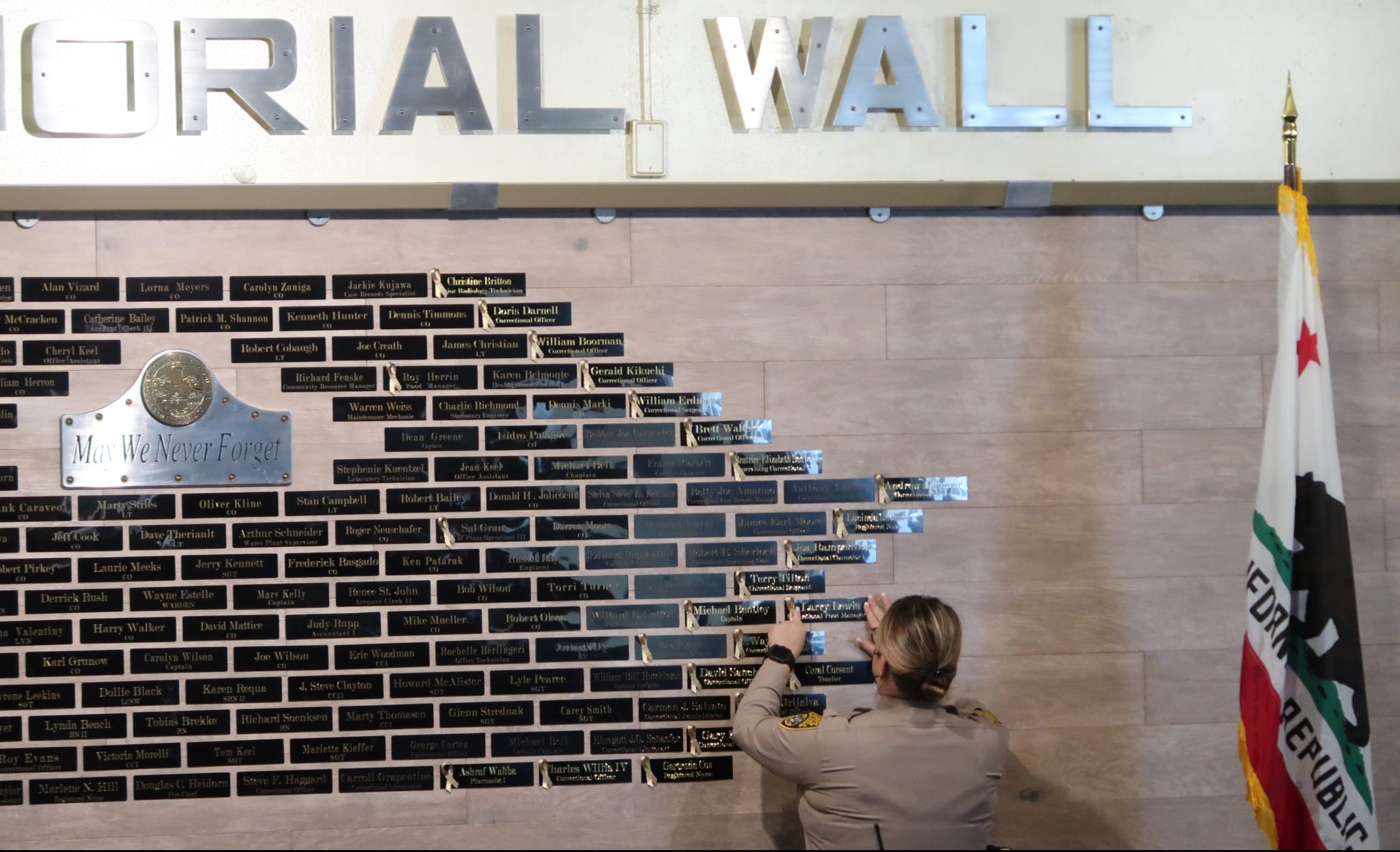 A staff member places a name on the memorial wall at CMC.