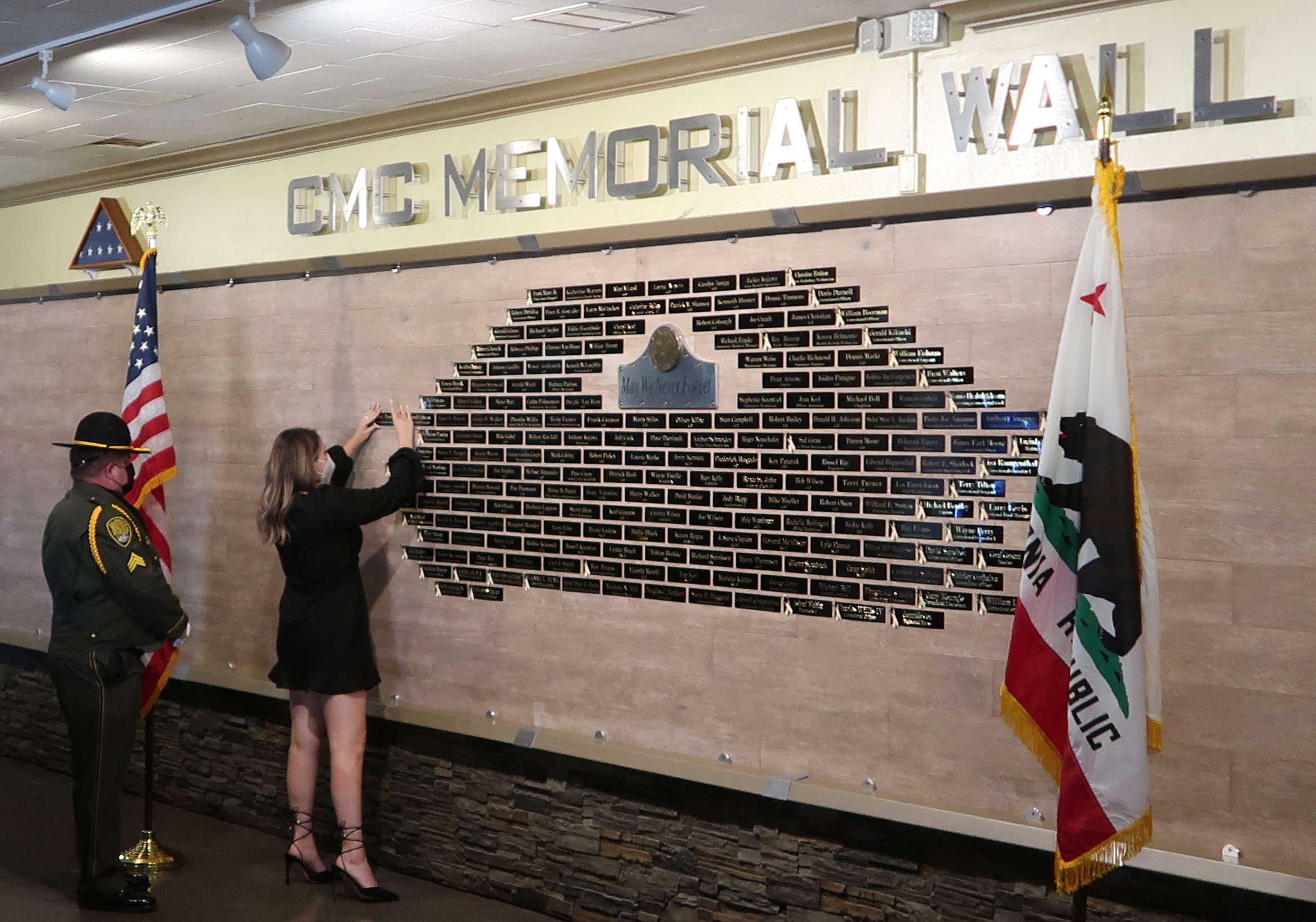 Woman places a nameplate on a memorial wall.