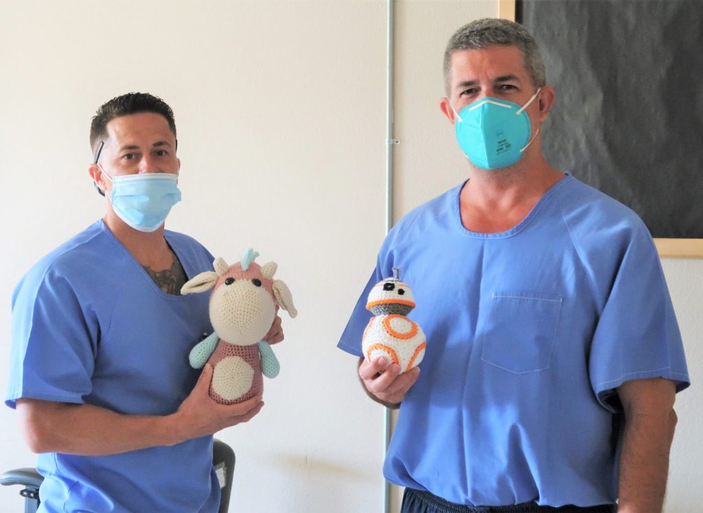 Two incarcerated men hold stuffed toys.