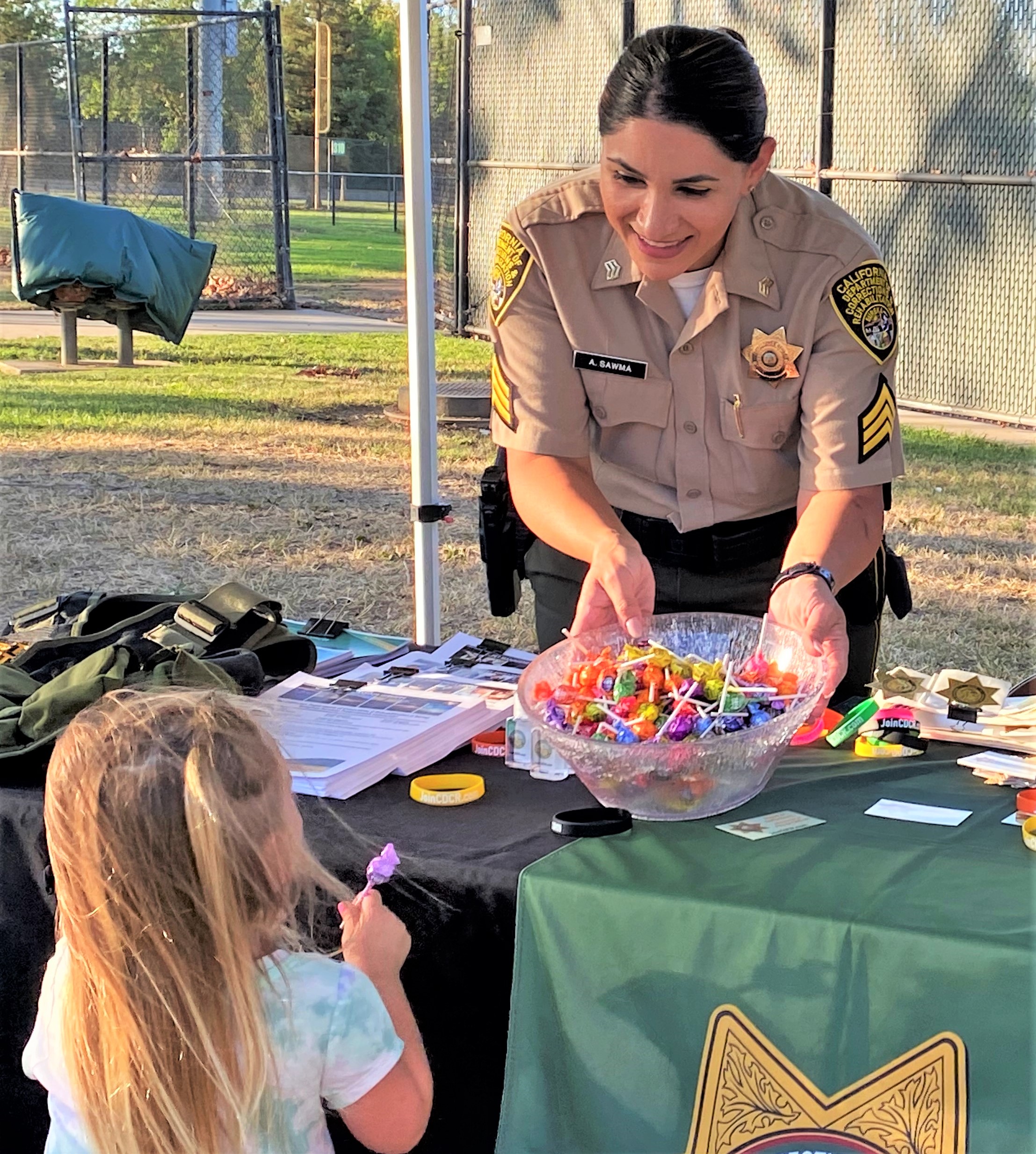Correctional sergeant holds a bowls of candy for a child.