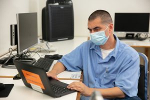 Incarcerated student uses computer as part of laptops project.