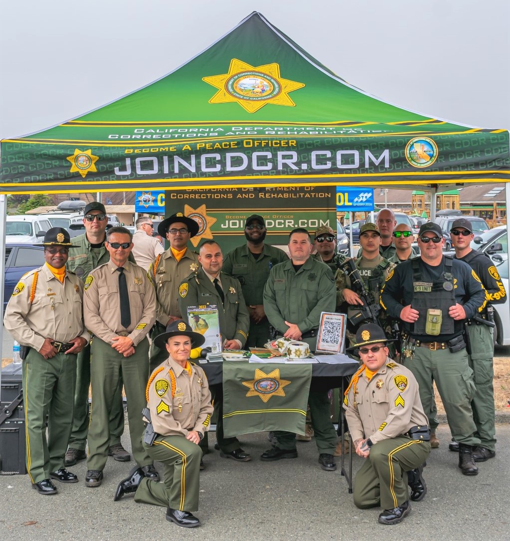 CDCR staff stand under a tent with the words "joincdcr.com" emblazoned on the front.