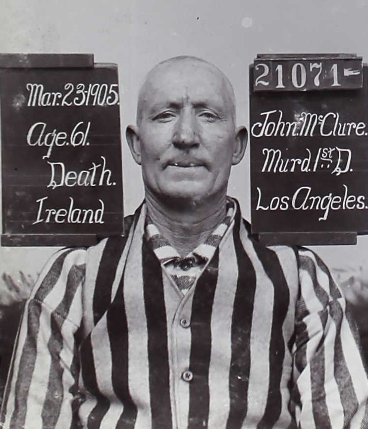 Mugshot of man wearing stripes with board for John McClure 21701.