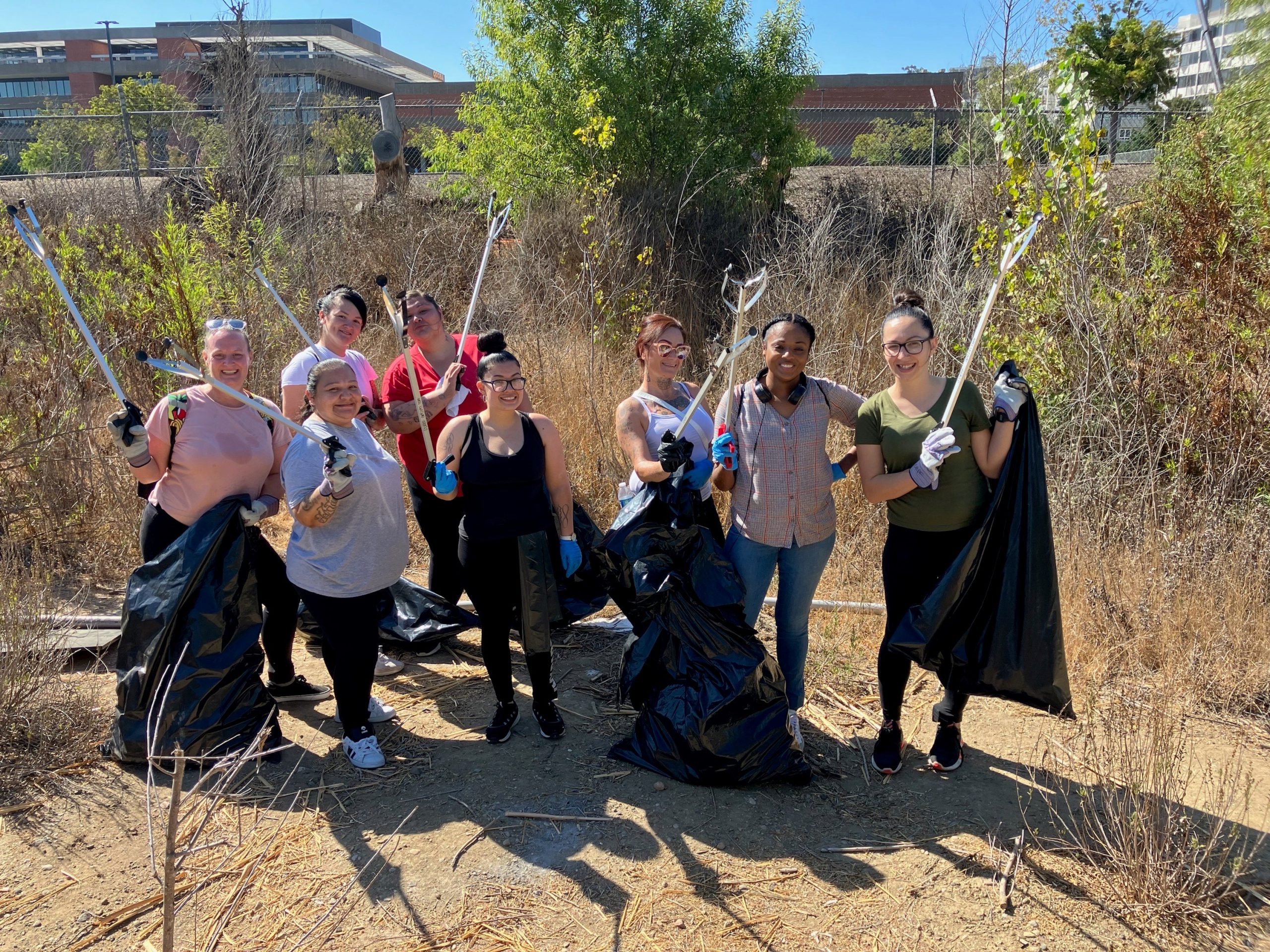 Re-entry program participants hold trash bags at San Diego River Basin.