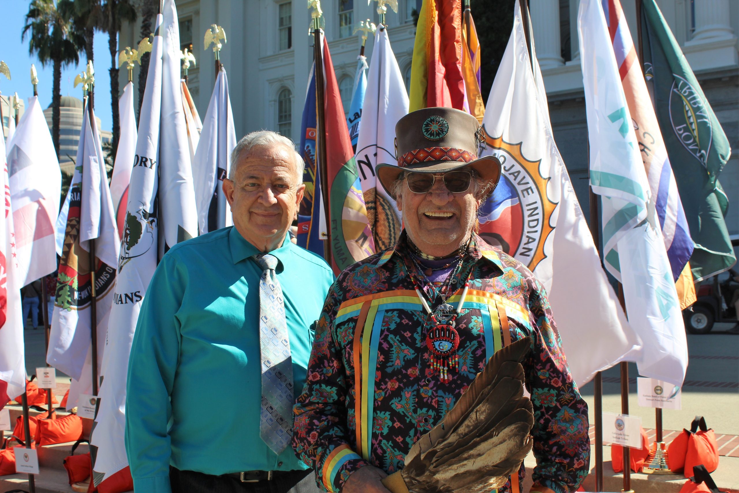 Two men, both CDCR staff, in front of Native American tribal flags.