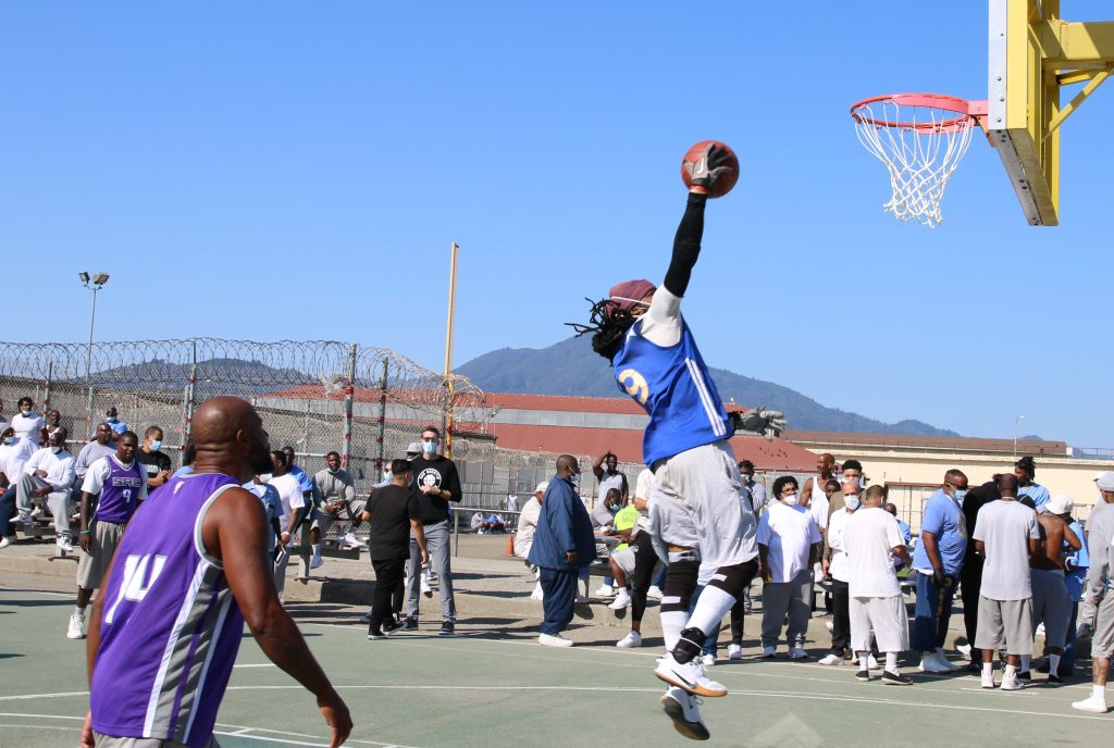 Man jumps toward basketball hoop while holding the ball.