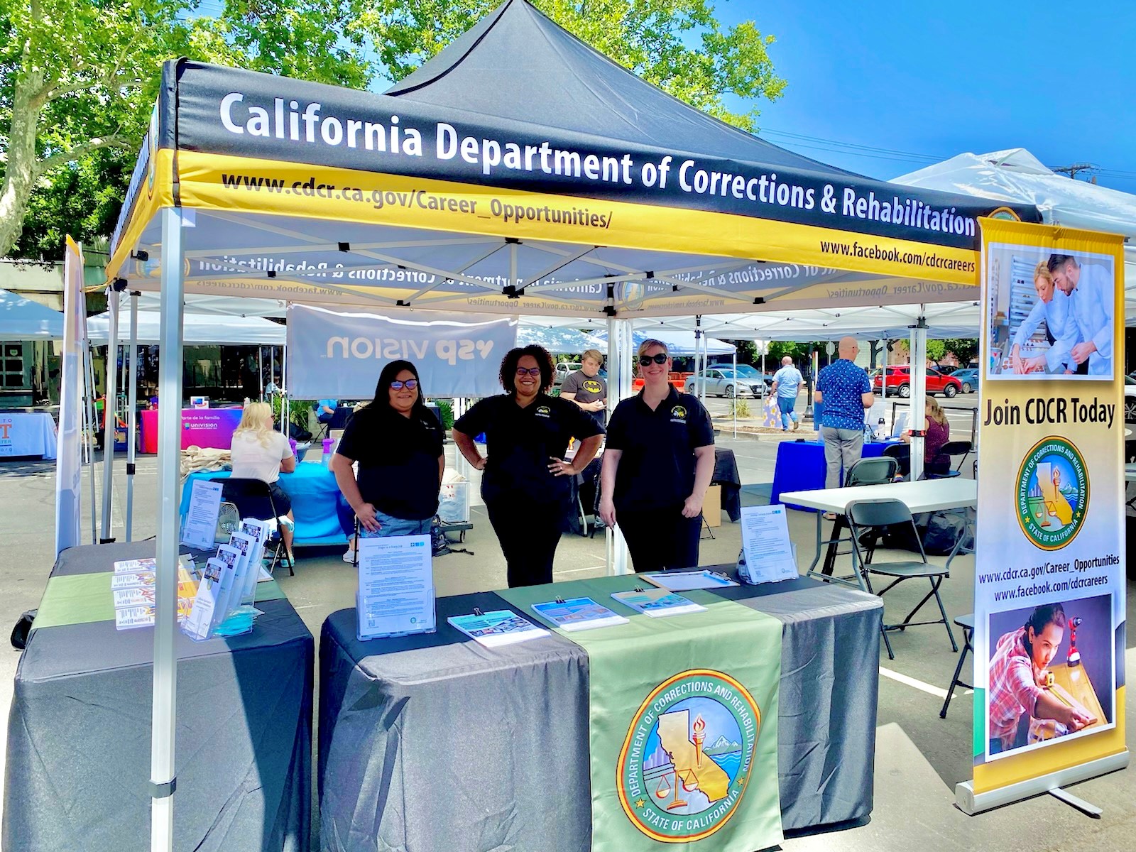 Three women wearing black shirts at a CDCR recruitment booth