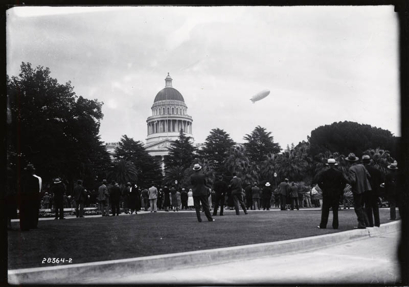 Large dirigible over California state capitol building.