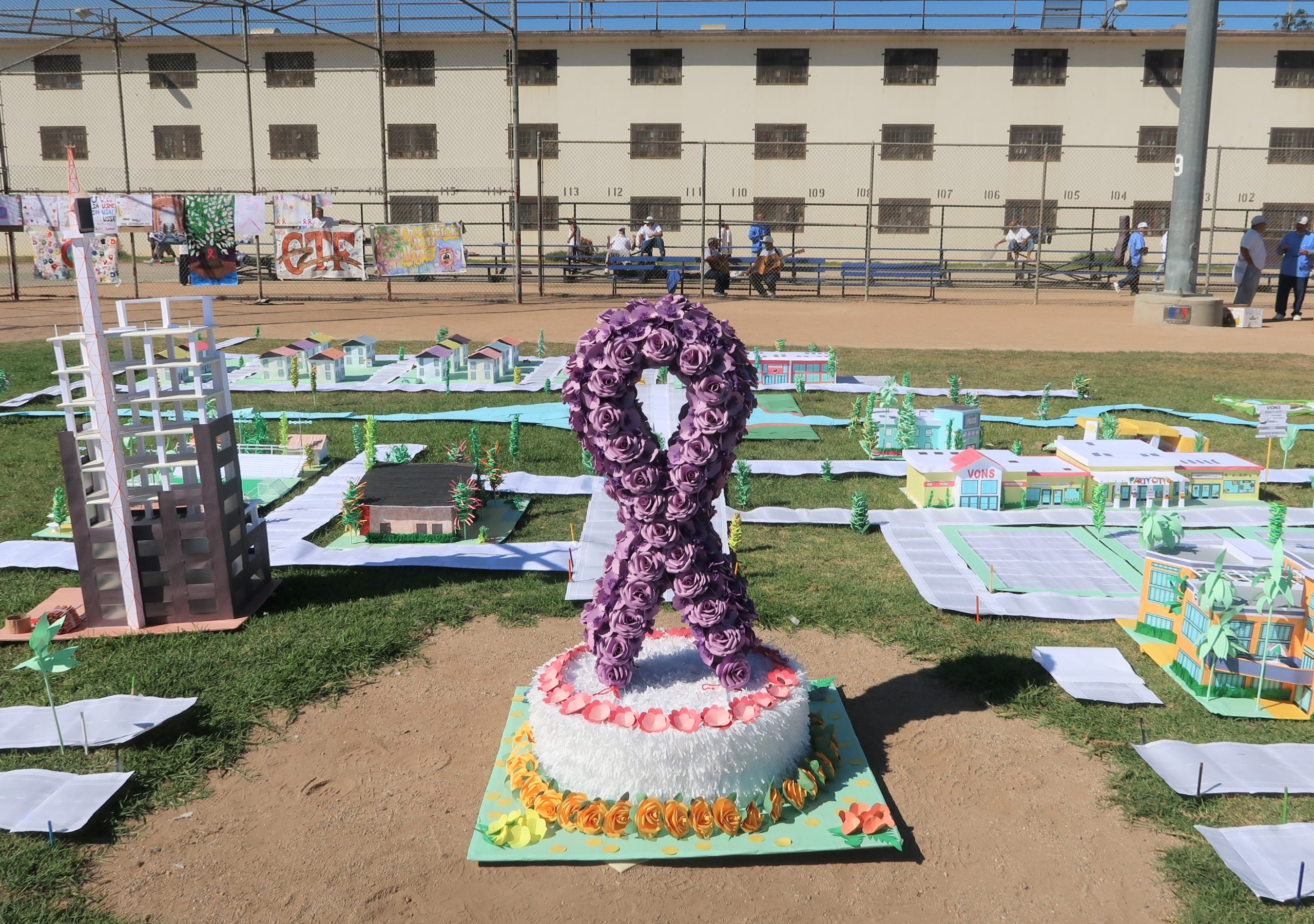 A purple ribbon and a city of paper in a prison yard.