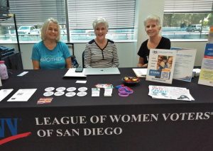Three women sit at a table for the League of Women Voters of San Diego.
