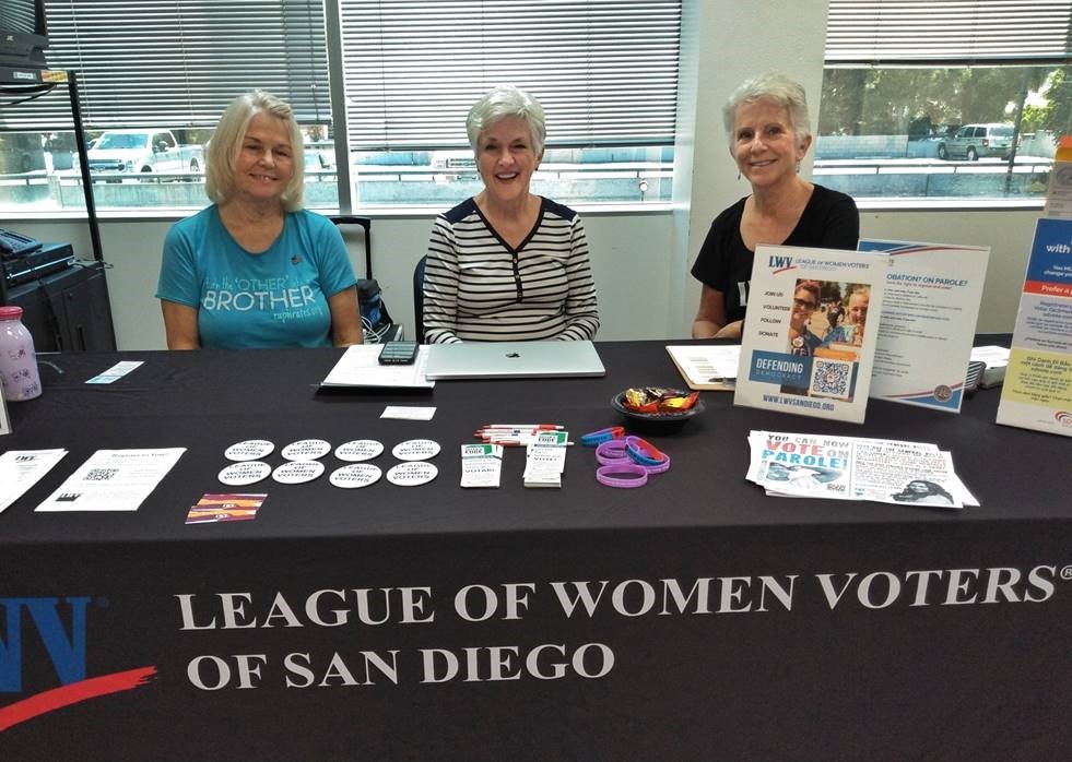 Three women sit at a table for the League of Women Voters of San Diego.