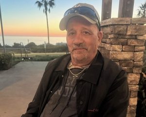 Frank Gomes sitting near beach at sunset.
