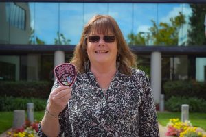 Woman holds a breast cancer awareness pink CDCR patch.