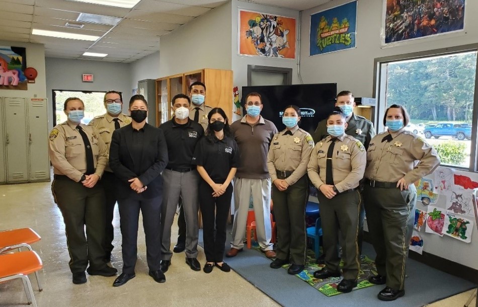 Officers and staff in a prison visiting room.