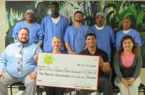 Prison warden, two men and inmate council members standing behind them.