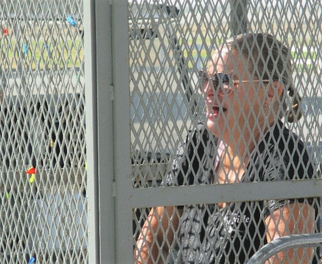 Woman in cage laughing as water balloons are thrown at her.