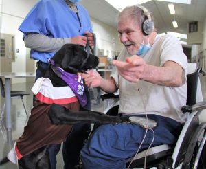 Dog greets a man in a wheelchair.