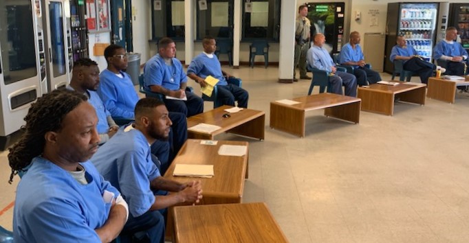 Incarcerated men sit in a semi-circle.