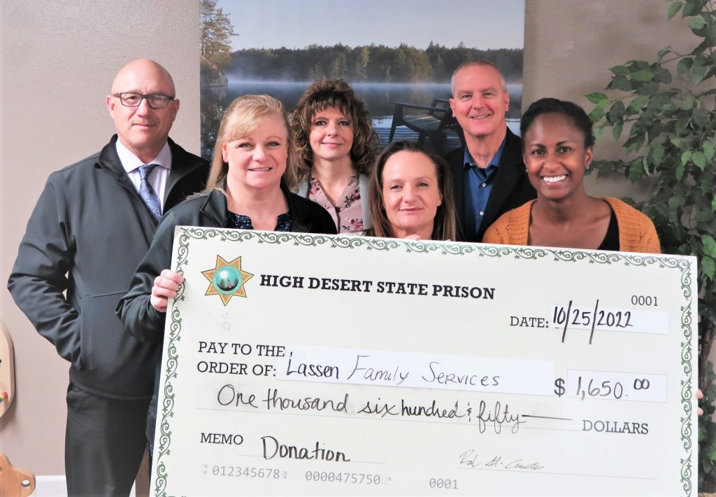 Six people hold a check from High Desert State Prison made out to Lassen Family Services.