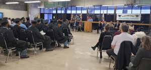 Rehabilitation graduation at California State Prison, Sacramento, with people in chairs and one speaking at a table.