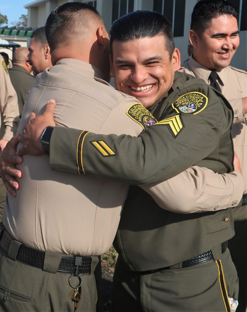 Sergeant hugs a new CDCR officer.