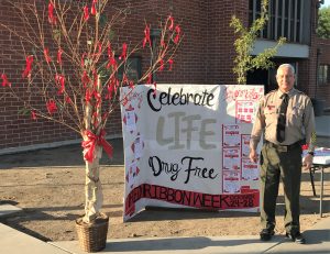 A tree covered in red ribbons and a banner with one CIW employee in uniform.