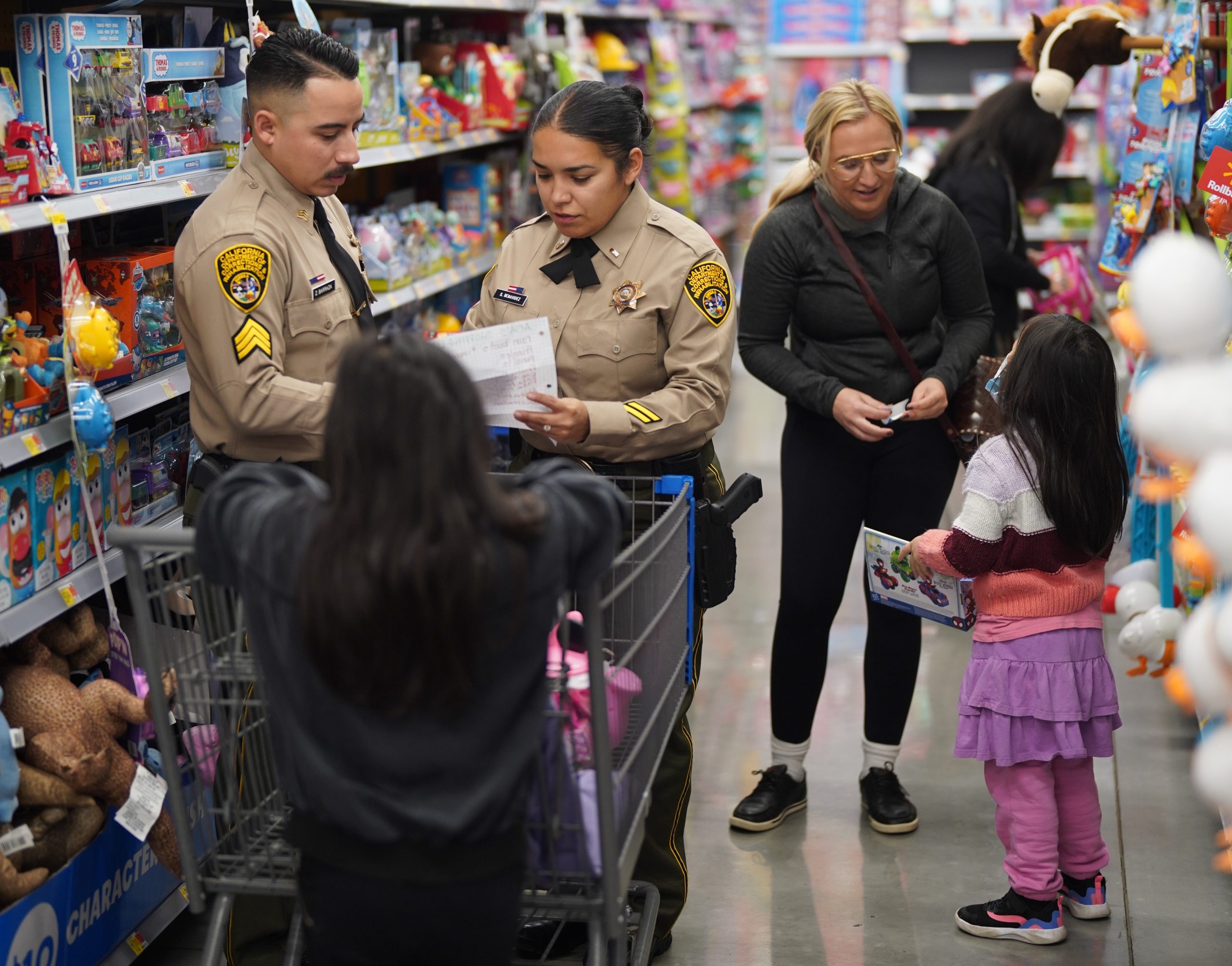 Two people in CDCR uniforms and a person in regular clothes with two children in a store.