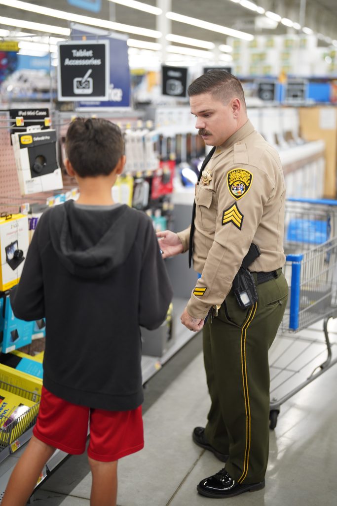 Man in CDCR uniform and a kid in a store.