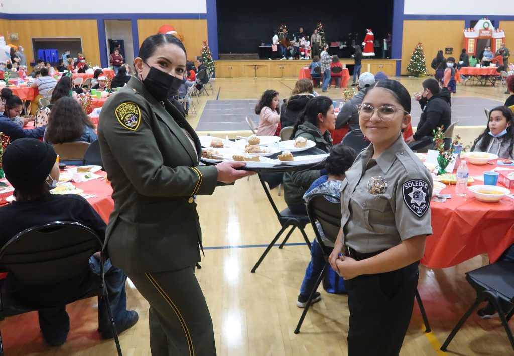 CDCR officer and Soledad police officer serve families at a holiday event.