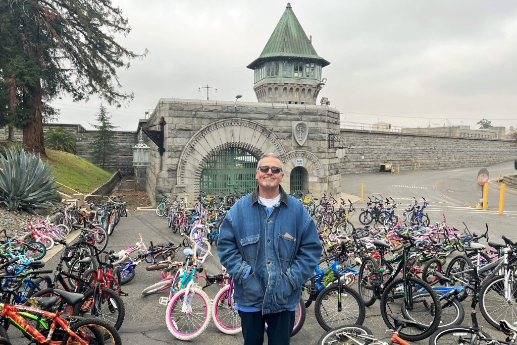 Incarcerated person with 200 refurbished bikes in front of Folsom prison.