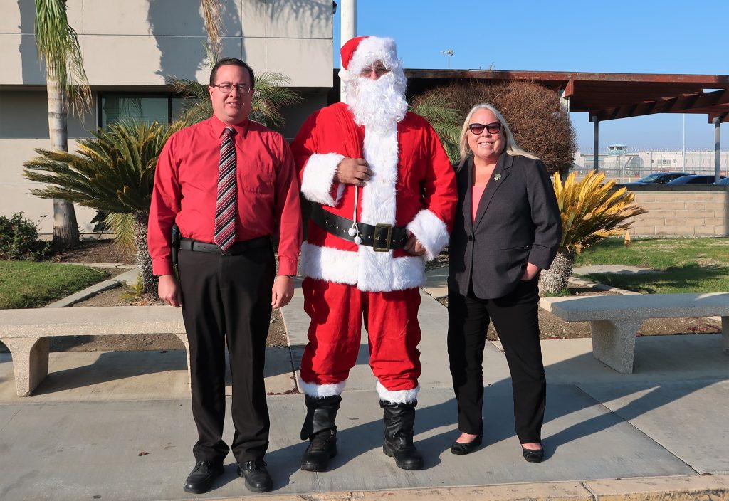 Two people stand with Santa outside North Kern State Prison.