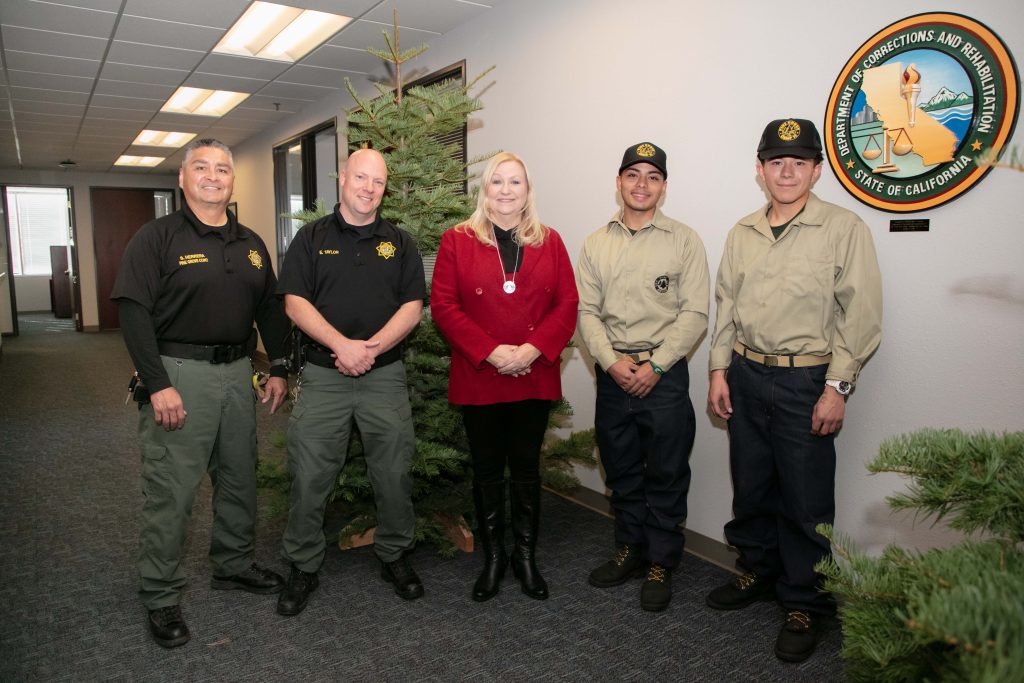 Correctional staff with Secretary and two Pine Grove camp youth with holiday trees.