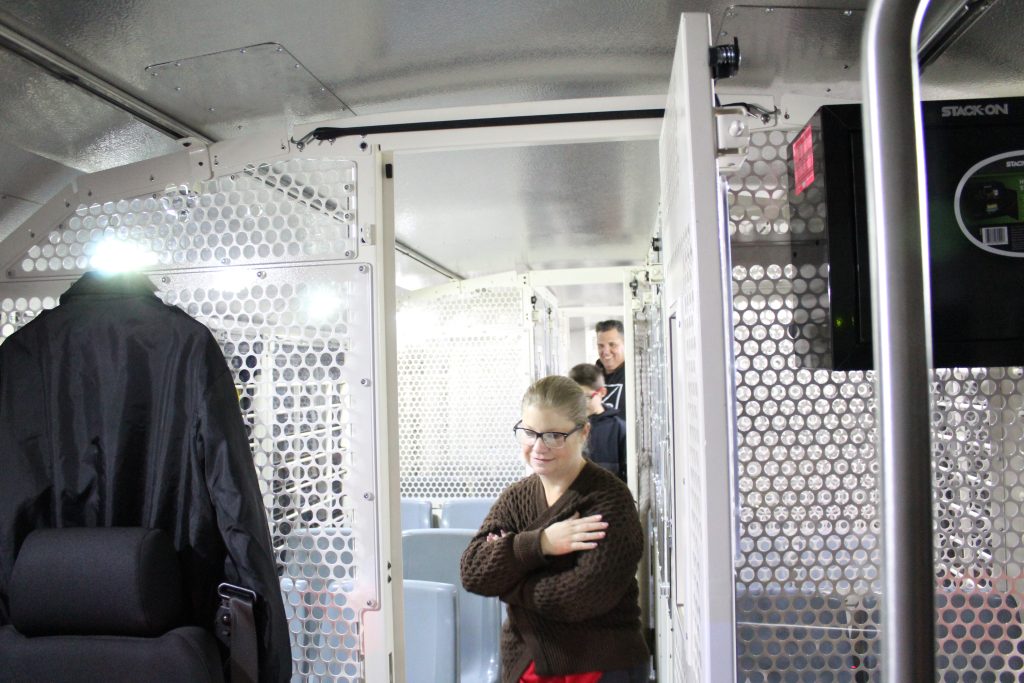 People walk through a prison bus.