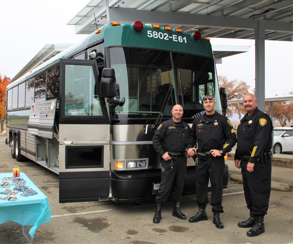 PVSP Transportation Unit Bus with three staff standing in front.