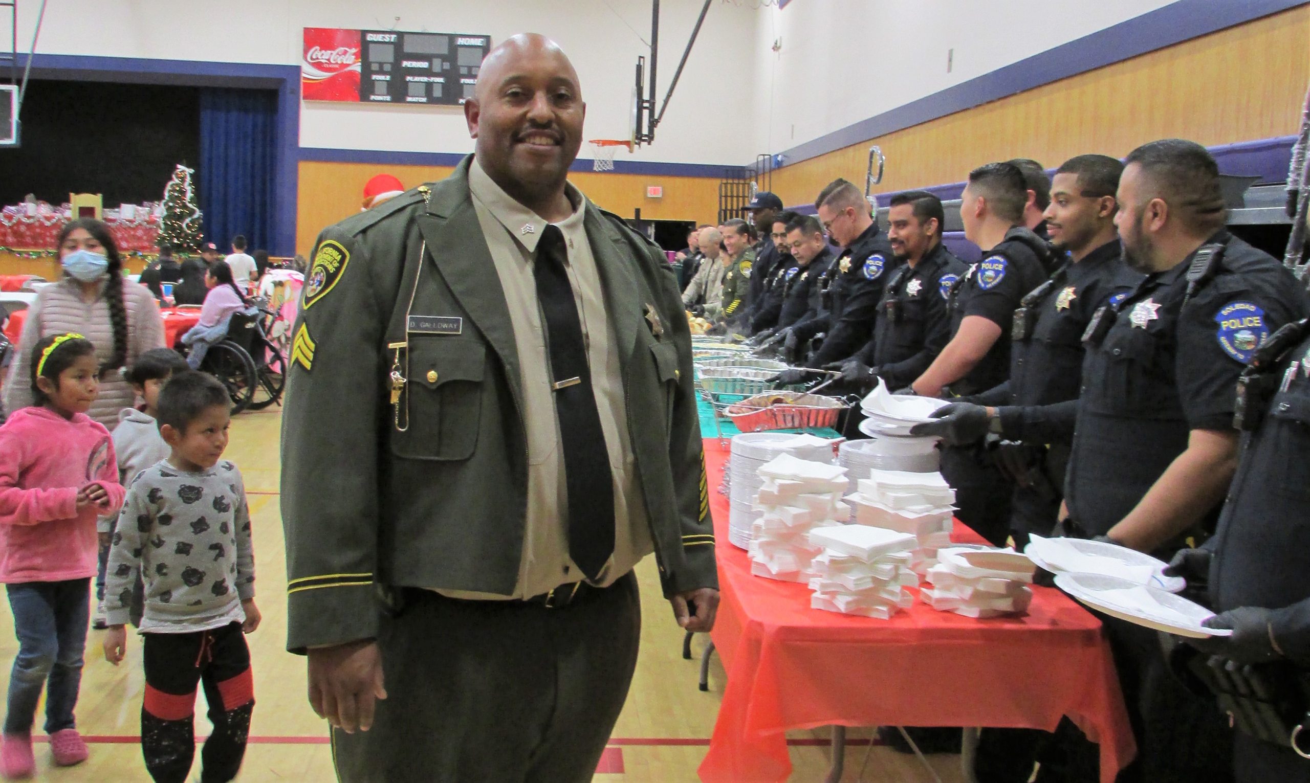 Prison sergeant stands beside the serving line at a community holiday dinner.