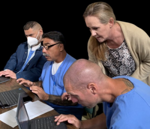 A woman helps three incarcerated people use their laptops
