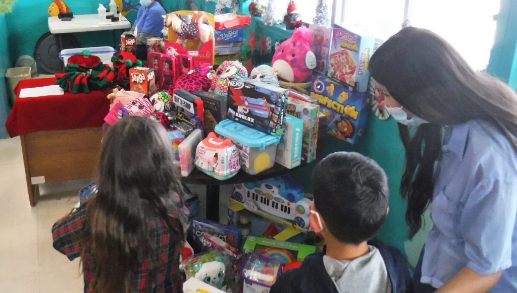 Children and incarcerated people in a visiting room with toys for Christmas.