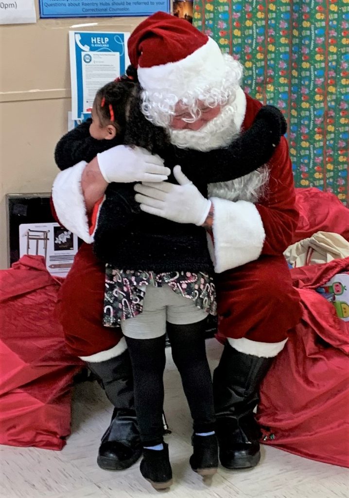 Christmas Day visiting toy drive with Santa hugging a child at CTF.