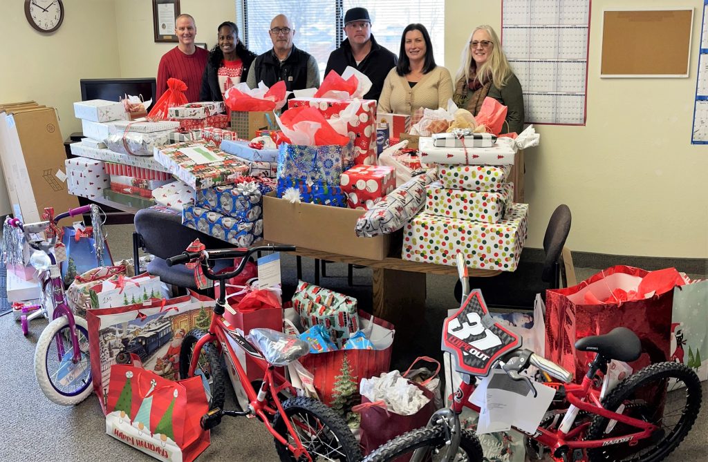 High Desert State Prison staff stand behind a table full of Christmas gifts.