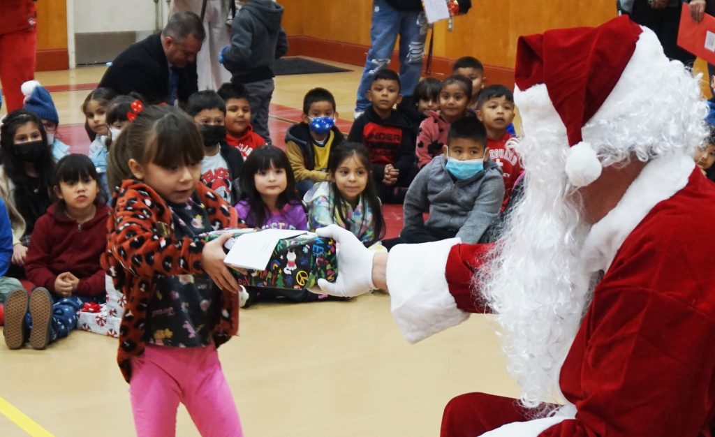 A child accepts a wrapped present from Santa.