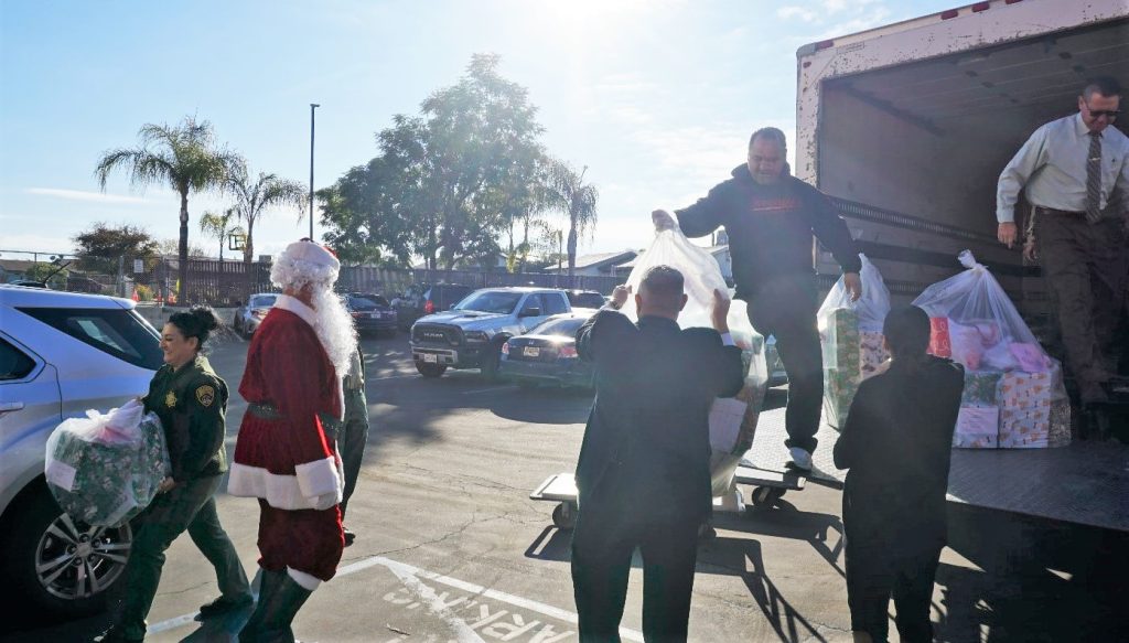 Kern Valley prison staff and Santa unload gifts from a box truck.