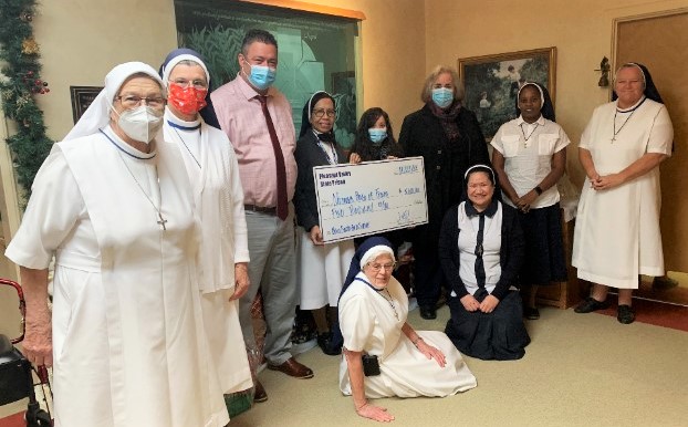 Nuns and prison staff with oversized donation check.