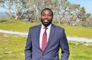 Acting regional health care executive Bayode Omosaiye wearing suit with trees and grass behind him.