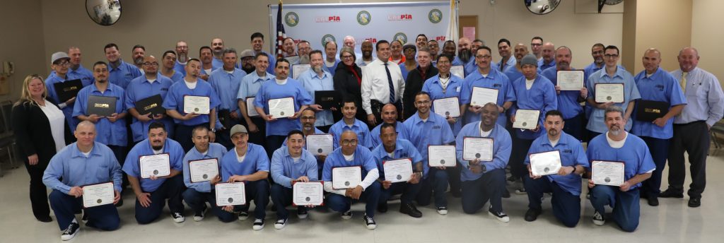 Incarcerated participants holds certificates at CALPIA graduation.