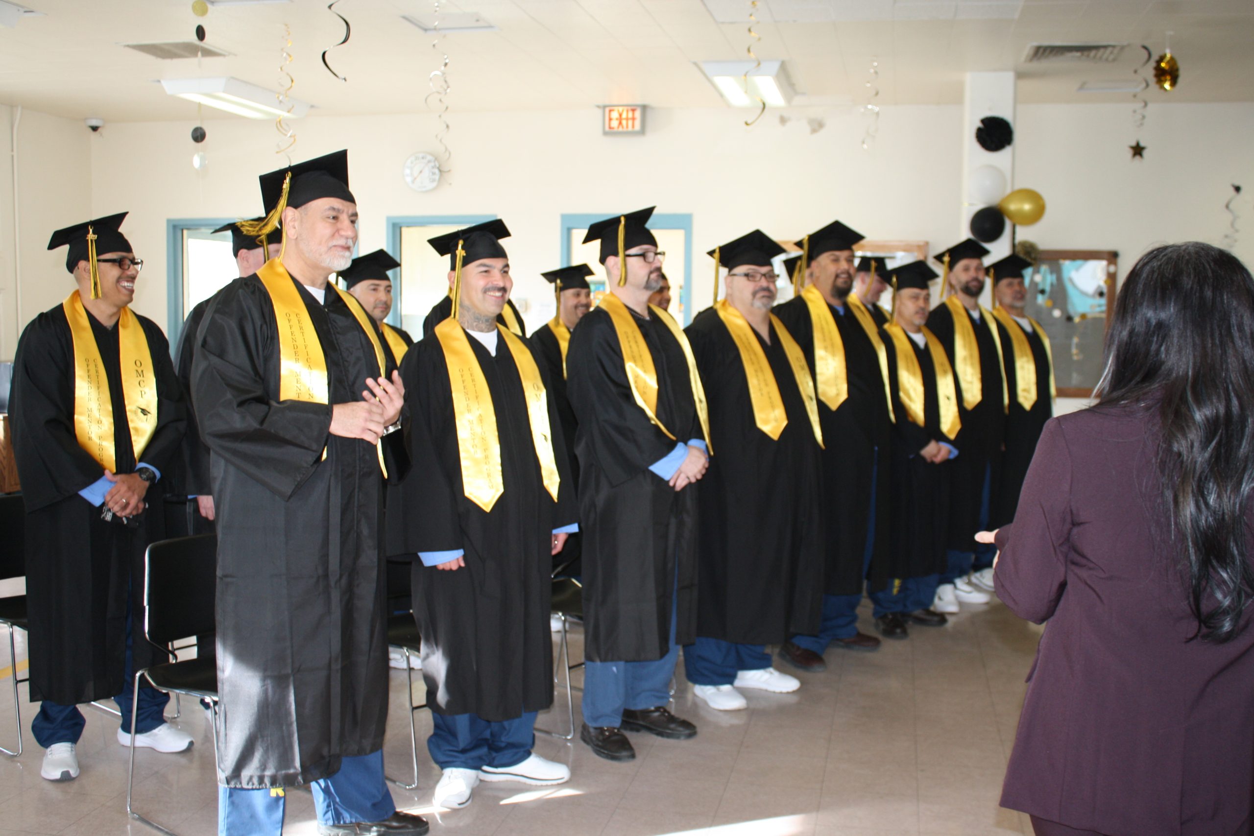 Offender Mentor Certification graduation with people wearing caps and gowns.