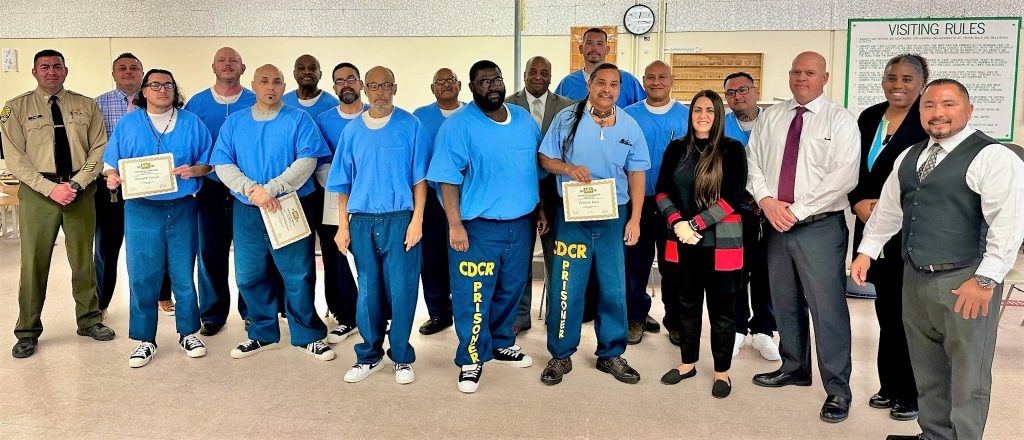 A group of men with some holding certificates in California State Prison Corcoran.